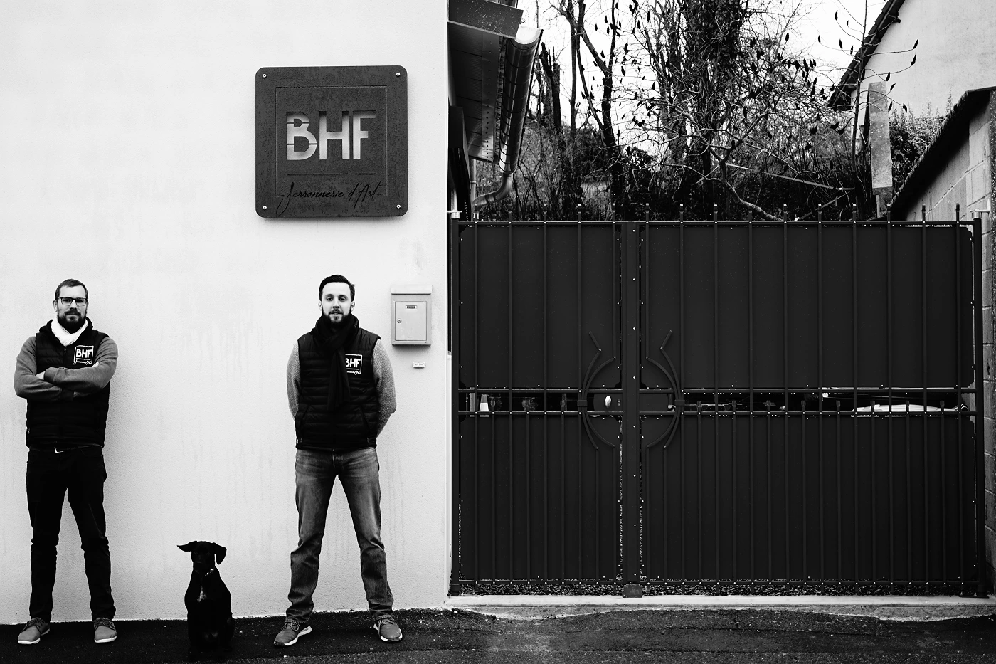Photo en noir et blanc de Christophe Hiegel et Denis Bardou devant le portail de BHF à Thil